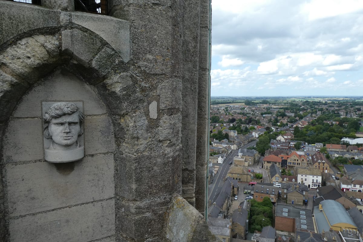 A carved head high on the tower, looking out over the town far below