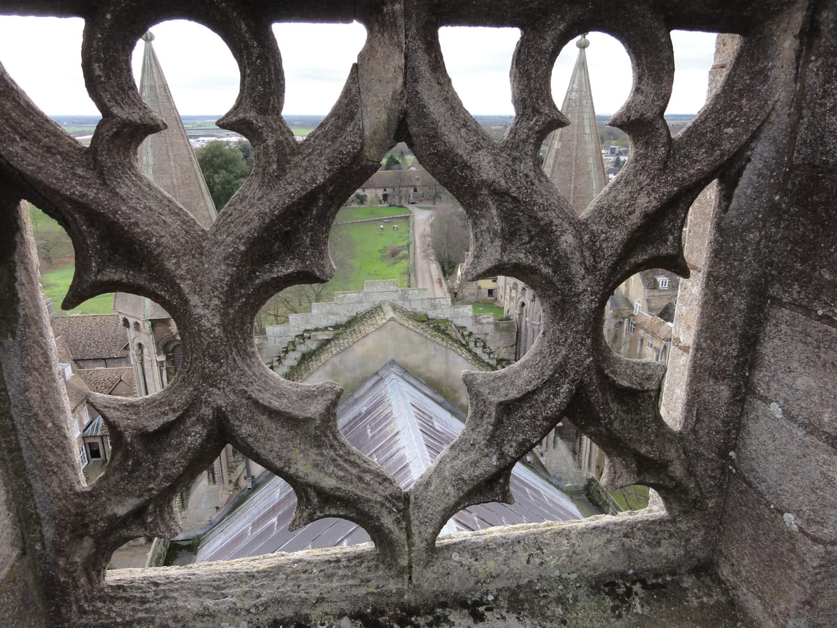 The fens, through the stone tracery of the parapet