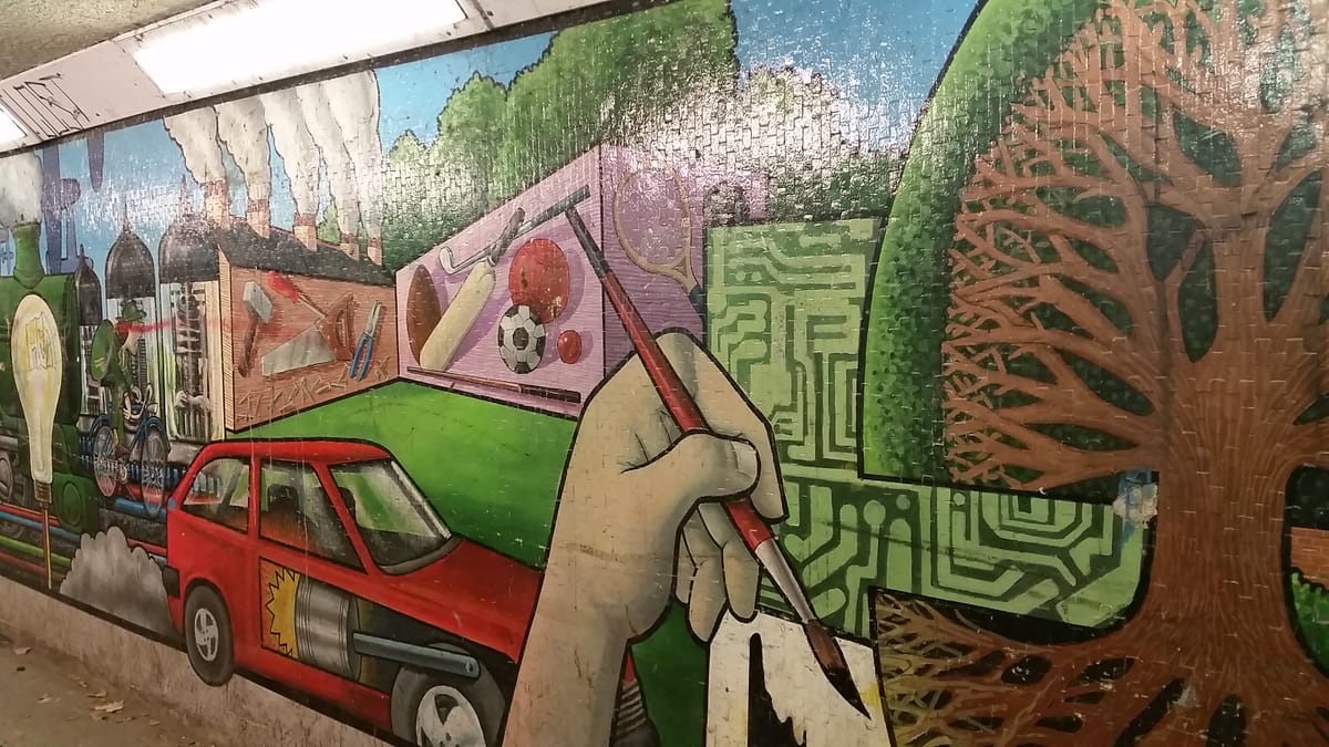 A painted hand at work, among a combustion engined car, sport and circuitry
